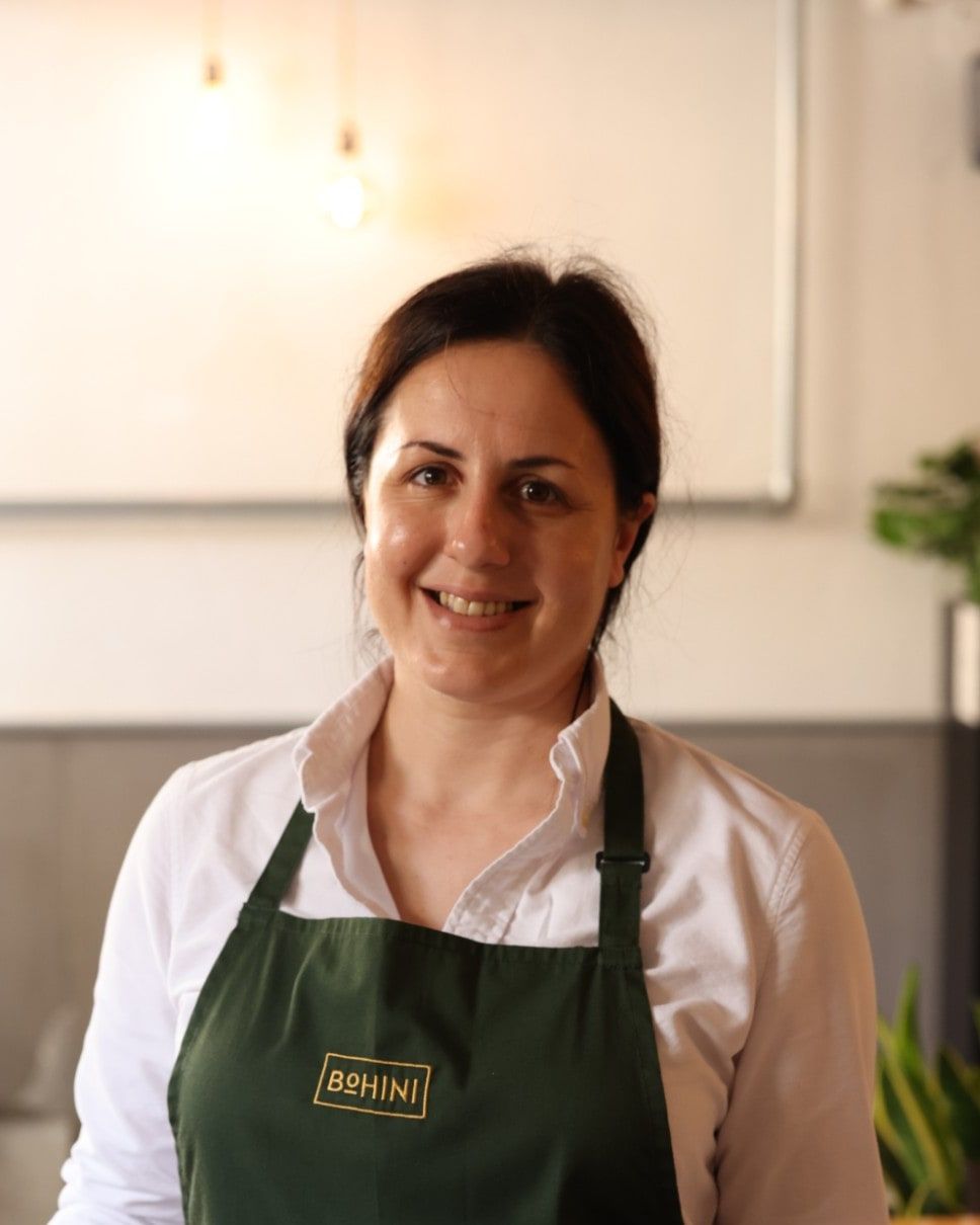 Marija Grech, titolare di Bohini, sorridente con il grembiule verde di Bohini dentro il locale