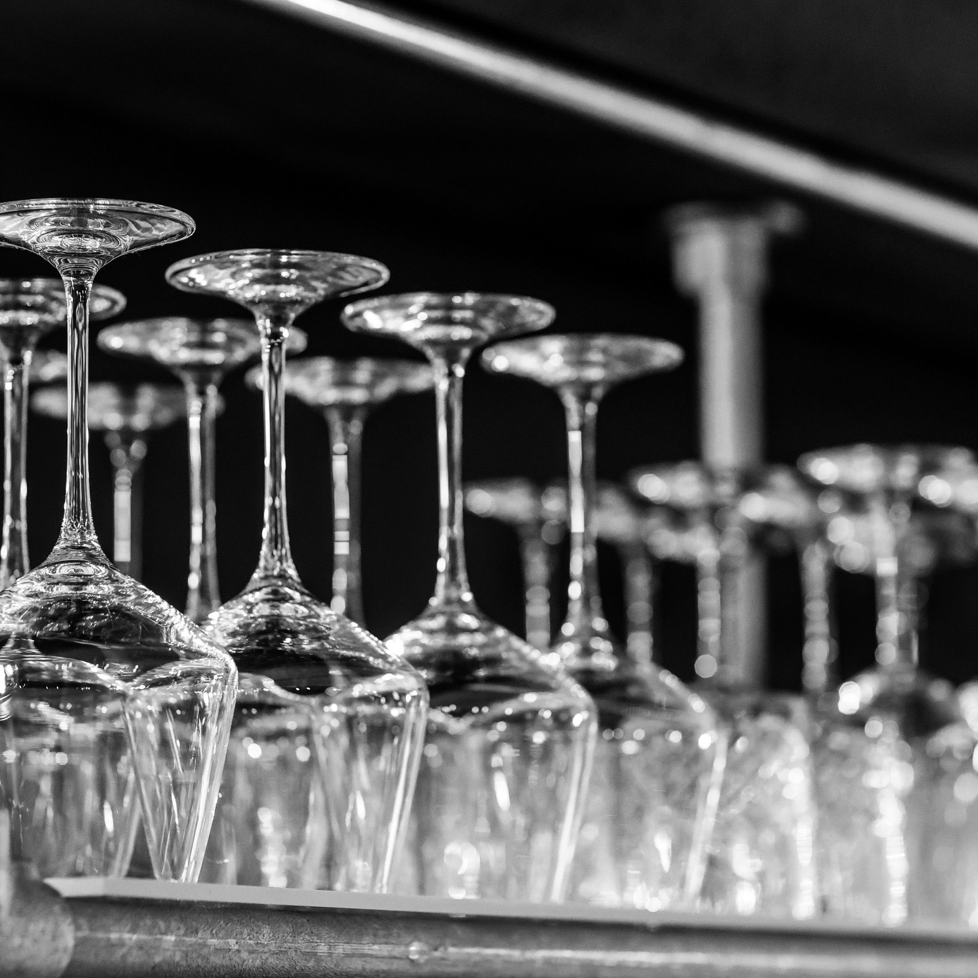 Wine glasses hanging upside down above the Bohini bar, in black and white